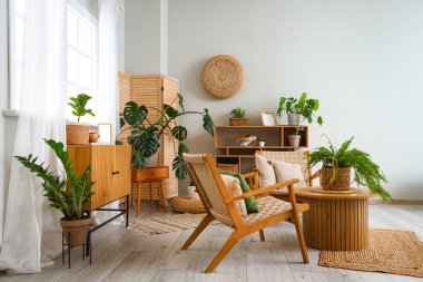 Interior of living room with green plants, table and armchairs