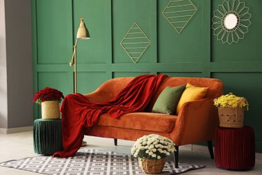 Portakal rengi kanepe ve kasımpatı çiçekleri olan modern oturma odasının içinde.