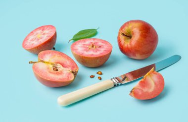 Mavi arkaplanda tohum ve yaprak olan tatlı pembe elmalar