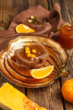 Tatlı kabak reçelli tost tabağı ve ahşap zemin üzerinde portakal.