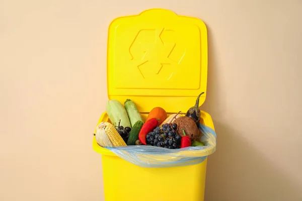 Container for garbage with waste food near beige wall. Recycling concept