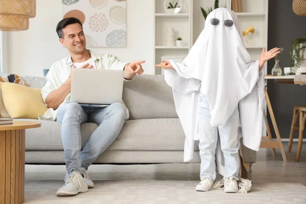 Funny little girl in ghost costume with her dad at home