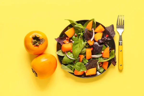 Plaat Van Heerlijke Salade Met Persimmon Granaatappel Zaden Gele Achtergrond — Stockfoto