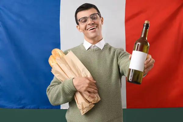 Young man with baguettes and champagne against flag of France