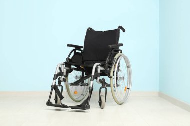 Mavi duvarın yanındaki boş tekerlekli sandalye.