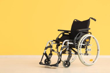 Sarı duvarın yanındaki boş tekerlekli sandalye.