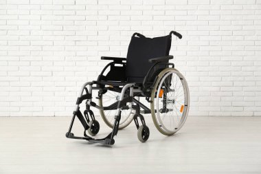 Beyaz tuğla duvarın yanında boş tekerlekli sandalye