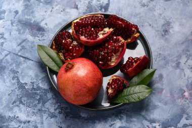 Taze nar ve mavi arka planda yapraklarla kaplı bir tabak.