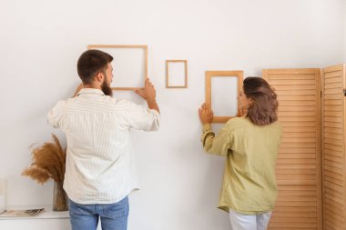 Mutlu çift birbirine aşık. Evlerinde, arka planda asılı çerçeveler.