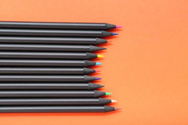 Turuncu arka planda birçok renkli kalemler