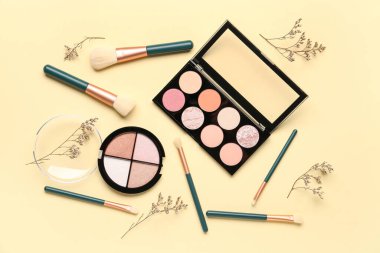 Makyaj ürünleri ve bej arka planda güzel çiçekler olan kompozisyon