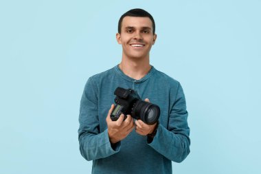 Mavi arka planda modern kameralı bir erkek fotoğrafçı.