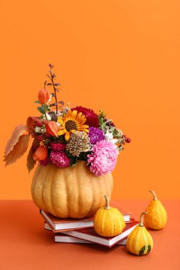 Balkabağında güzel bir sonbahar buketi ve turuncu arka planda kitaplar