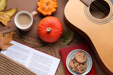 Kahve, kitap, gitar ve arka planda sonbahar dekoru içeren kompozisyon