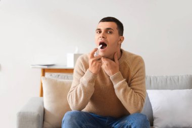 Evde boğaz ağrısı için sprey kullanan hasta bir genç.