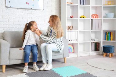 Ofiste küçük bir kızla çalışan olgun bir konuşma terapisti.