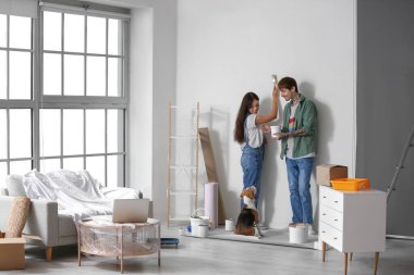 Yeni evlerinin tamiri sırasında Beagle köpeğiyle duvar boyayan genç çift.