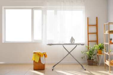 Ütü masası ve çamaşır sepetinin olduğu odanın içi.