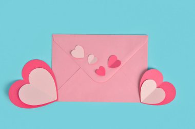 Mavi zemin üzerinde kağıt kalpler olan zarf