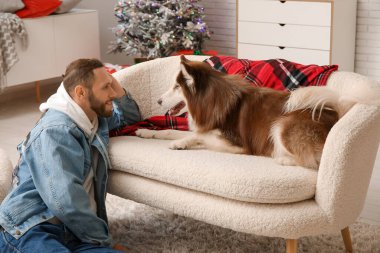 Evde sevimli köpekli yakışıklı bir genç adam.