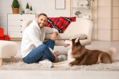 Evde sevimli köpekli yakışıklı bir genç adam.