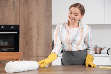 Mutfakta pp-tozu olan kadın hademe masasını temizliyor.