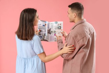 Pembe arka planda dergi okuyan genç bir çift.