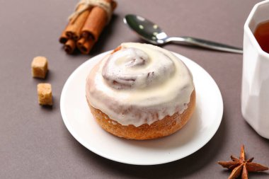 Kahverengi arka planda kremalı lezzetli tarçınlı rulo