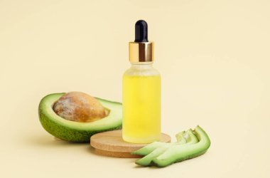 Ahşap tezgahlı taze avokado ve bej arka planda bir şişe gerekli yağ.