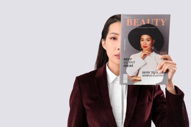 Beyaz arka planda güzellik dergisi olan genç Asyalı kadın.