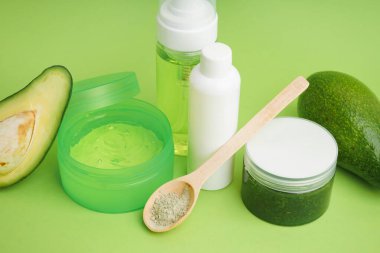 Yeşil zemin üzerinde kozmetik ürünler ve taze avokado seti