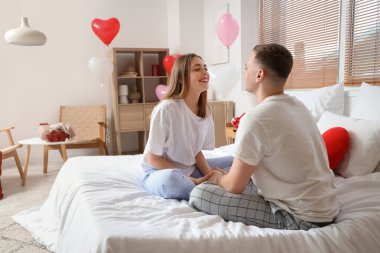 Yatakta oturup sevgililer gününü evde kutlayan güzel bir çift.