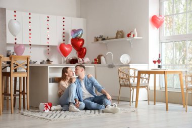 Güzel genç çift yerde oturuyor ve sevgililer gününü evde kutluyorlar.