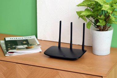 Yeşil duvarın yanındaki klozette bitki, dergi ve boya ile modern wi-fi yönlendirici