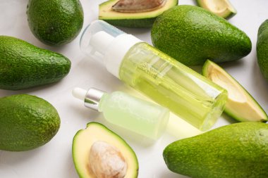 Taze avokadolar ve arka planda gerekli yağ şişeleri, yakın plan.