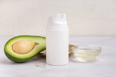 Taze avokado ve arka planda bir şişe kozmetik ürünü, yakın plan.