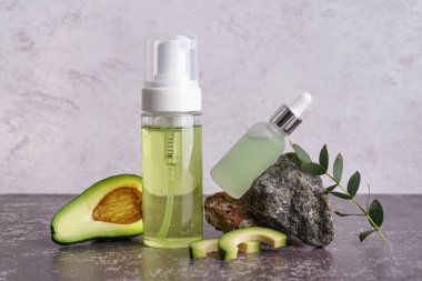 Taze avokado ve arka planda gerekli yağ şişeleri