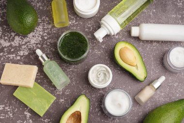 Taze avokadolu kompozisyon ve grunge arka planında farklı kozmetik ürünler