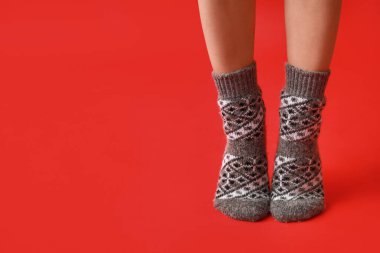 Kırmızı arka planda, sıcak gri çoraplı genç kadın bacakları.