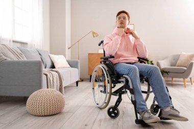 Evde tekerlekli sandalyede oturan genç adam.