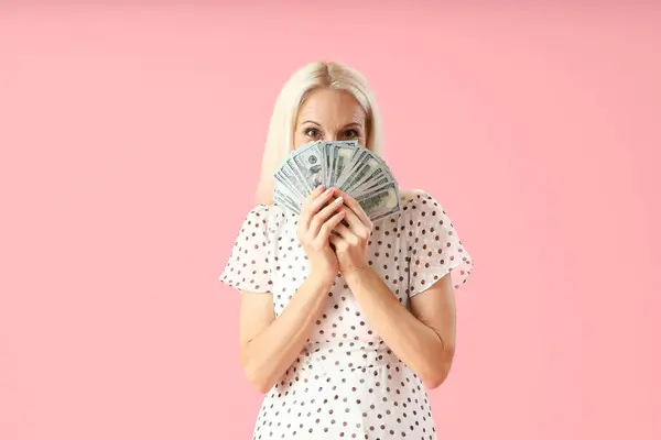 具有粉色背景的美元钞票的成熟妇女 — 图库照片