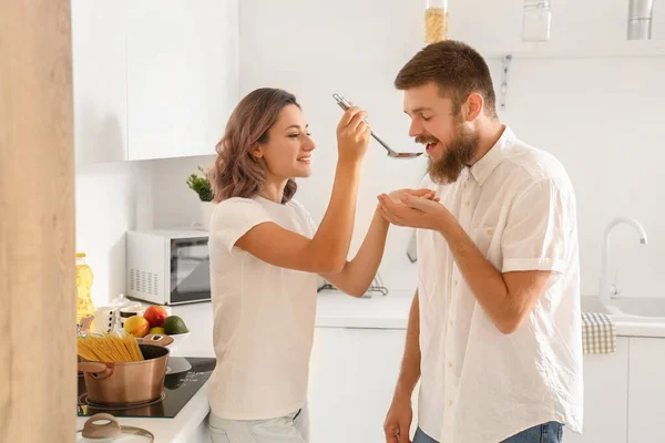 Happy couple in love tasting food in kitchen