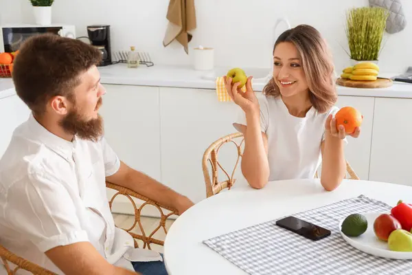 Happy couple in love with fruits in kitchen