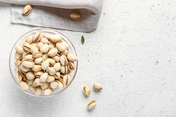 Beyaz arka planda fıstıklı cam kase.