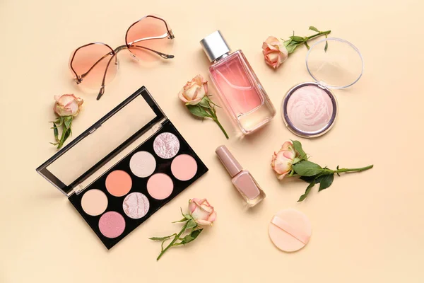 Composition with makeup products and beautiful rose flowers on beige background
