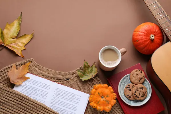 Composition with cup of coffee, book and autumn decor on color background