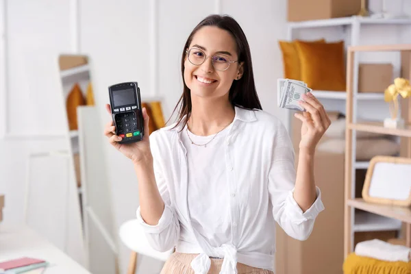 Female seller with payment terminal and money in warehouse store