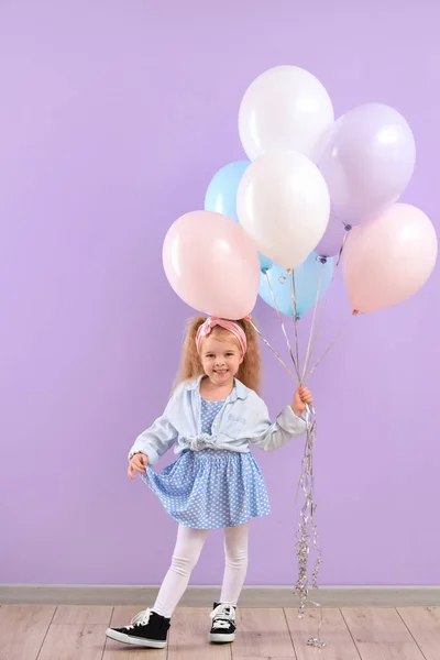 Cute little girl with beautiful balloons near purple wall