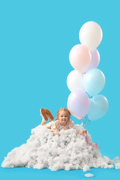Cute little girl with beautiful balloons lying on cloud against blue background