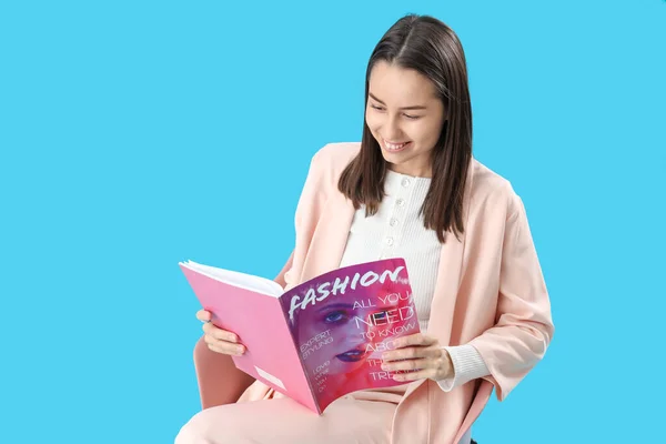 Junge Frau Liest Modezeitschrift Stuhl Auf Blauem Hintergrund — Stockfoto